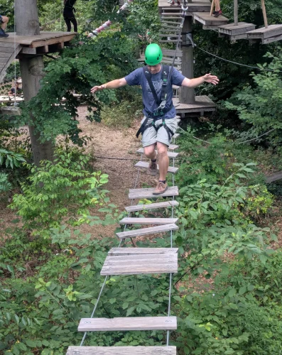 Person in einem Balancierhindernis im Kletterwald
